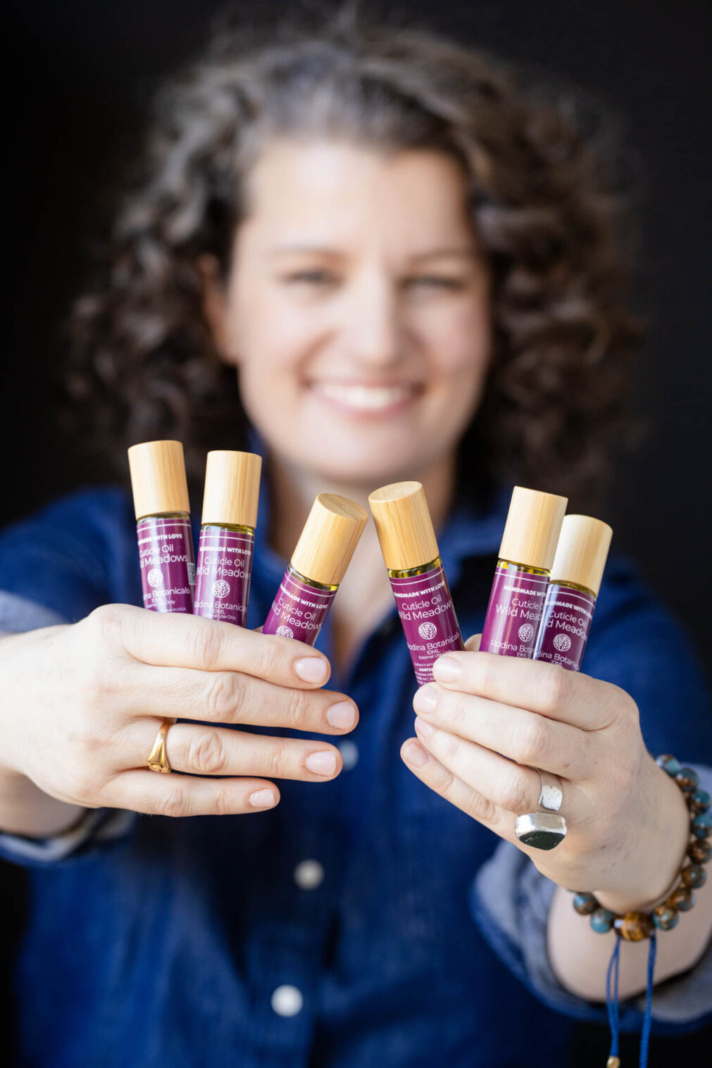 a woman holds bottles of cuticle oil up to the camera