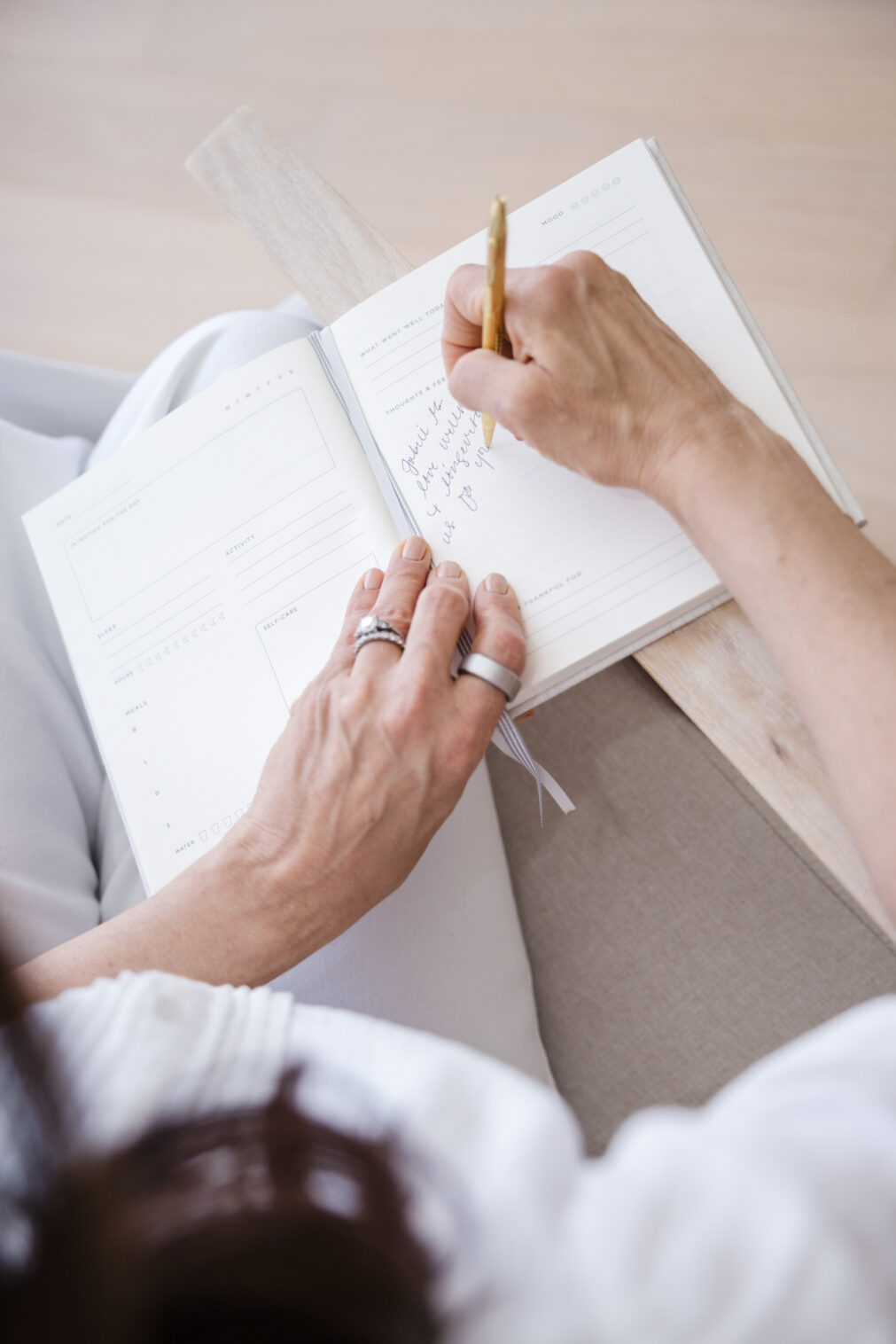 woman's hands writing in a journal from above