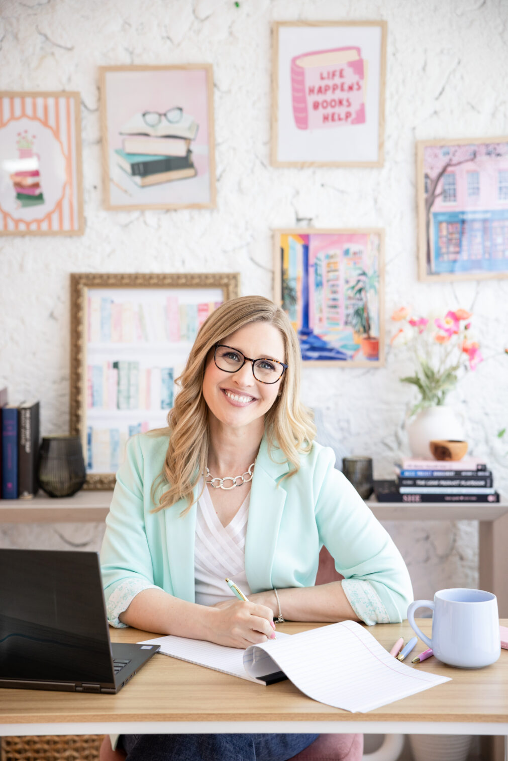 Woman writing in a notebook, surrounded by books and posters, smiling at the camera during a Chicago brand photography shoot.