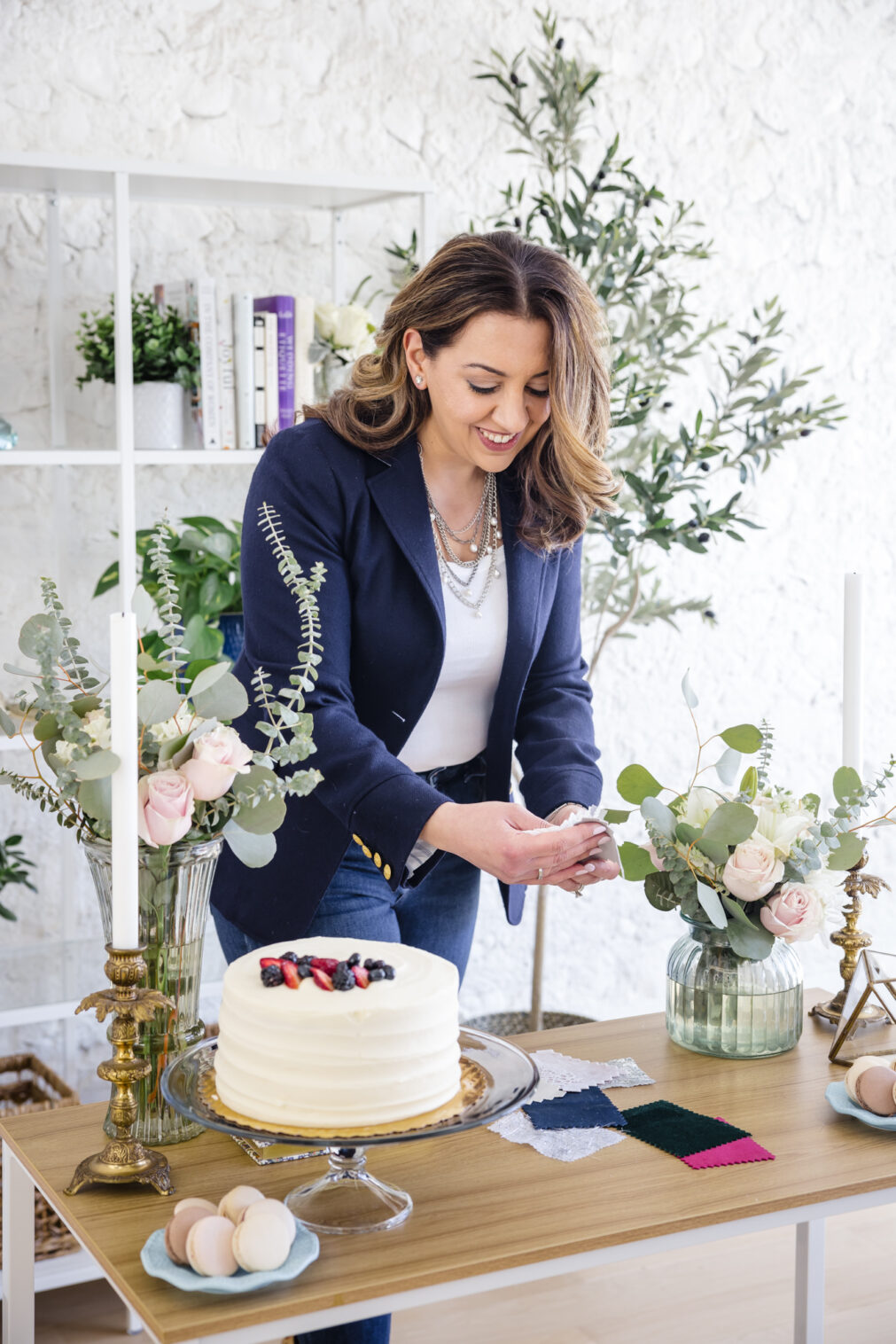 Woman sorting fabric samples at a desk with cake, flowers, and wedding décor during a Chicago brand photography session.
