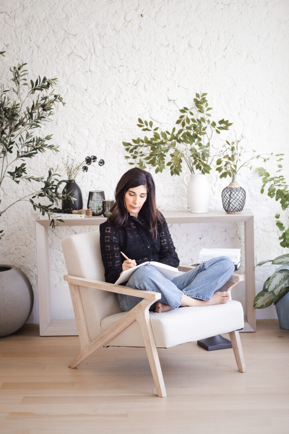 Woman sitting cross-legged in a chair while writing in a journal during a Chicago brand photography shoot.