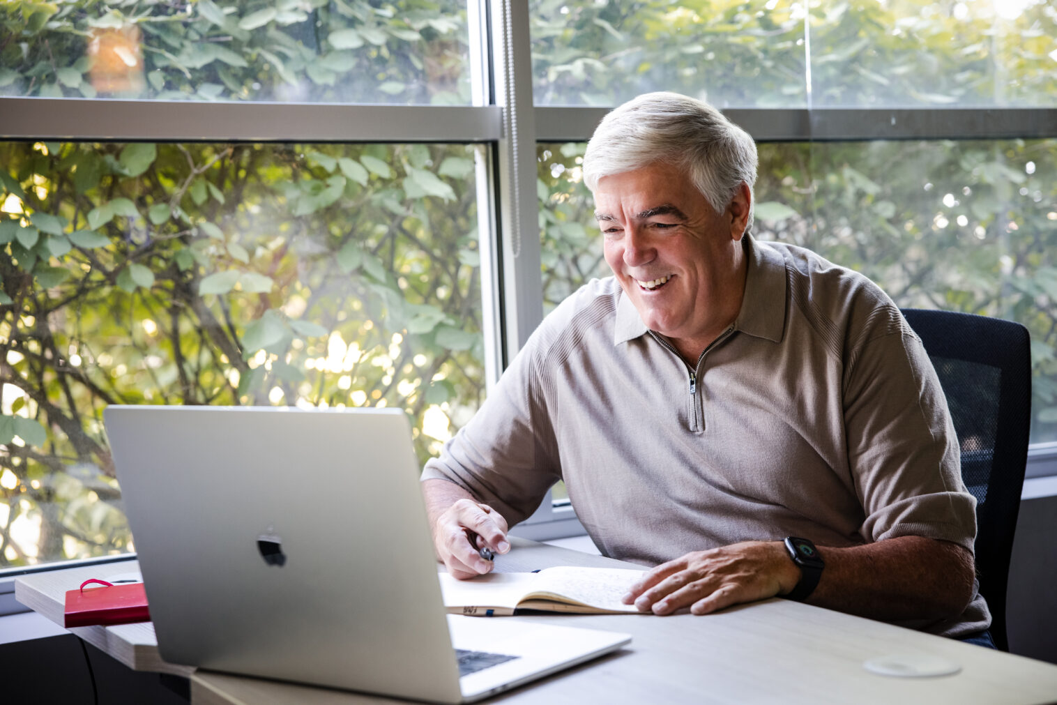man sits at desk looking at laptop