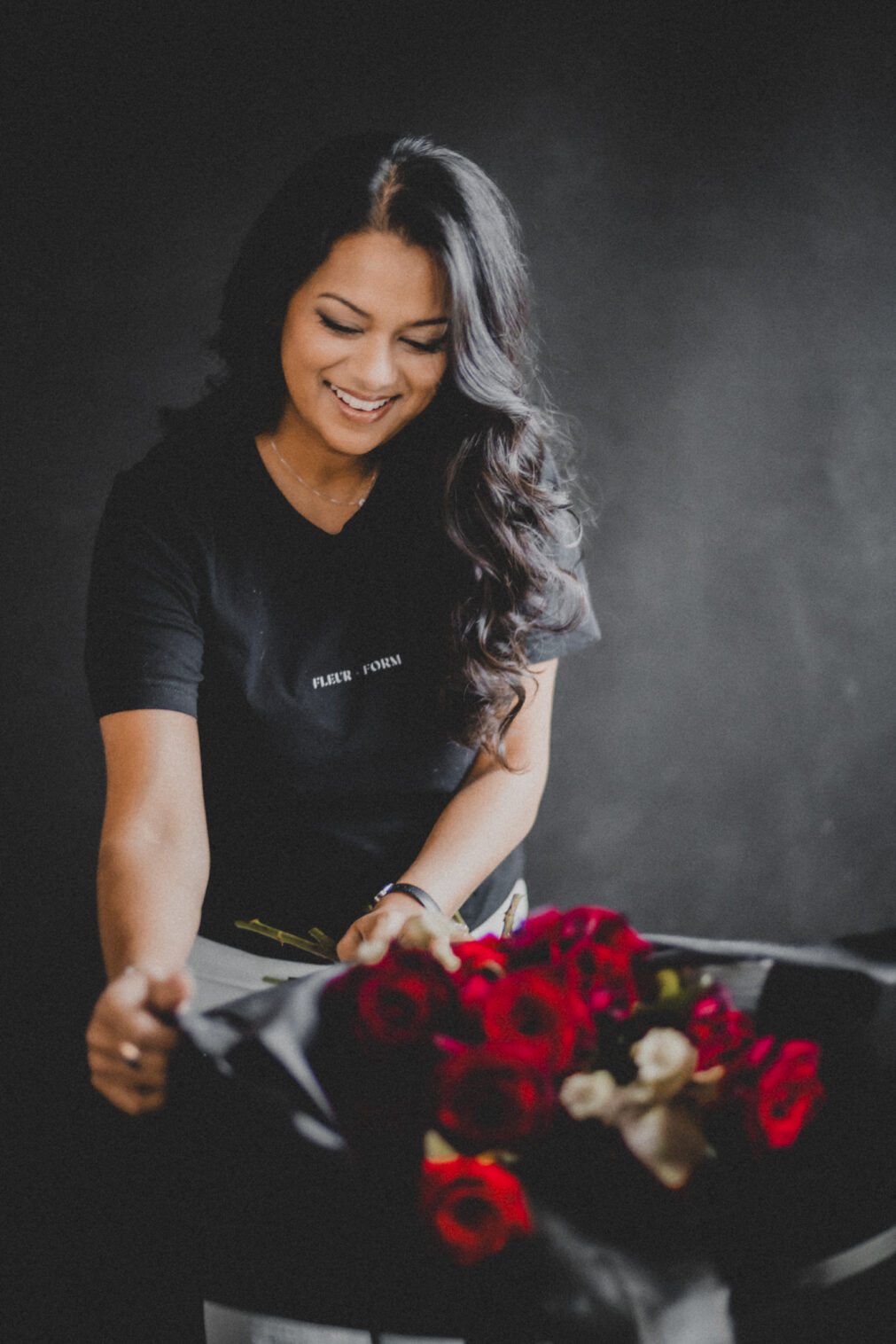 Dark and moody portrait of a Barrington, Illinois florist arranging red roses for a Valentine's Day arrangement