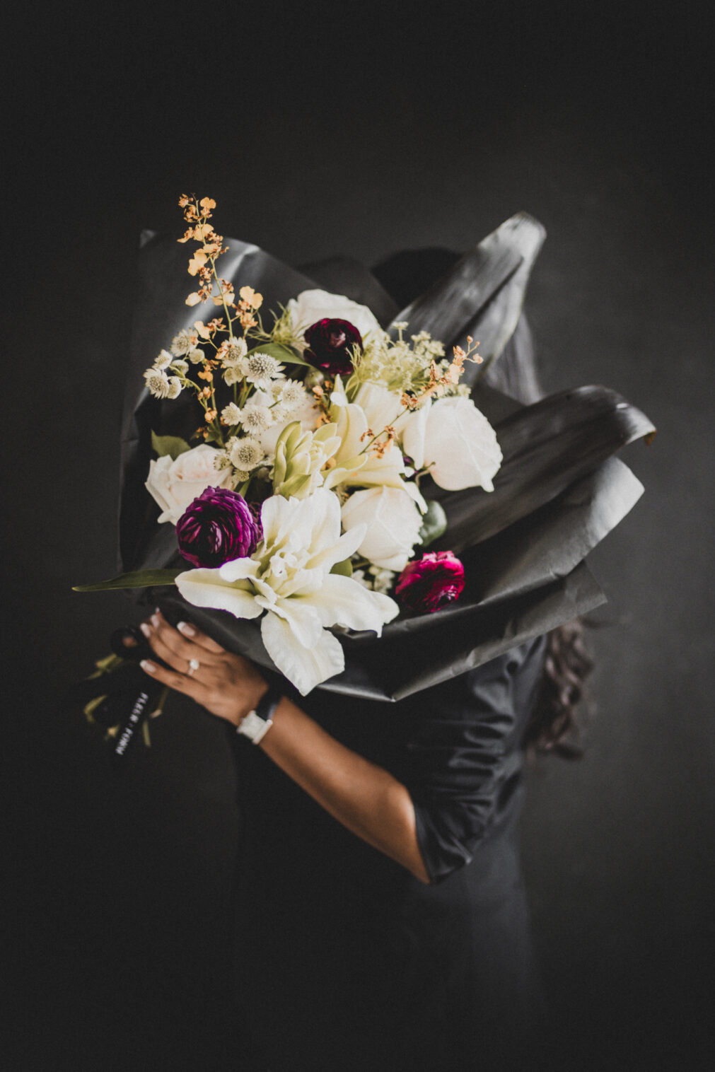Moody branding image of a Barrington florist working in her studio with Valentine’s Day flowers and low light.